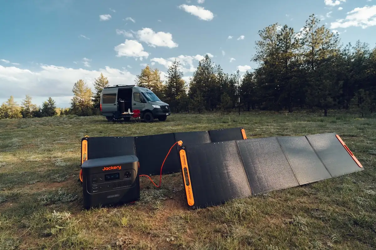 Jackery 2000 Plus power station with two solar panels charging at a campervan campsite