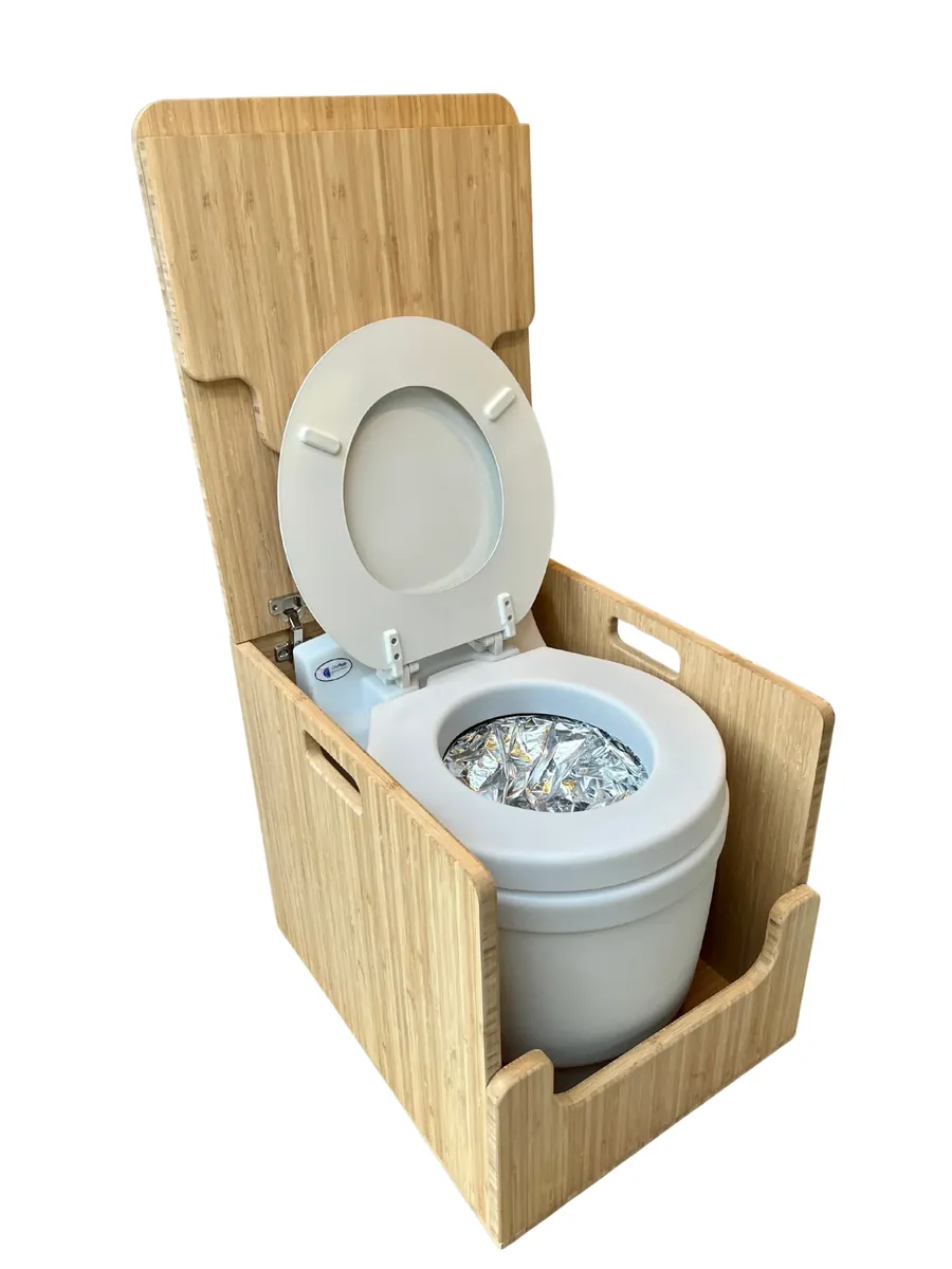 Laveo dry-flush toilet with the lid open showing the sealed bag cartridge inside, set in a bamboo cabinet