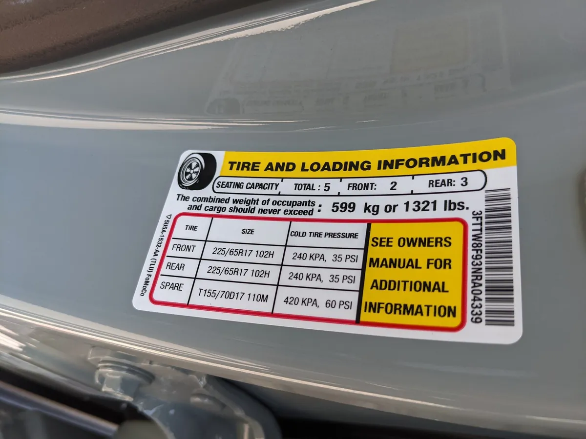 Close-up of a yellow tire and loading information placard on a truck door jamb showing payload limit