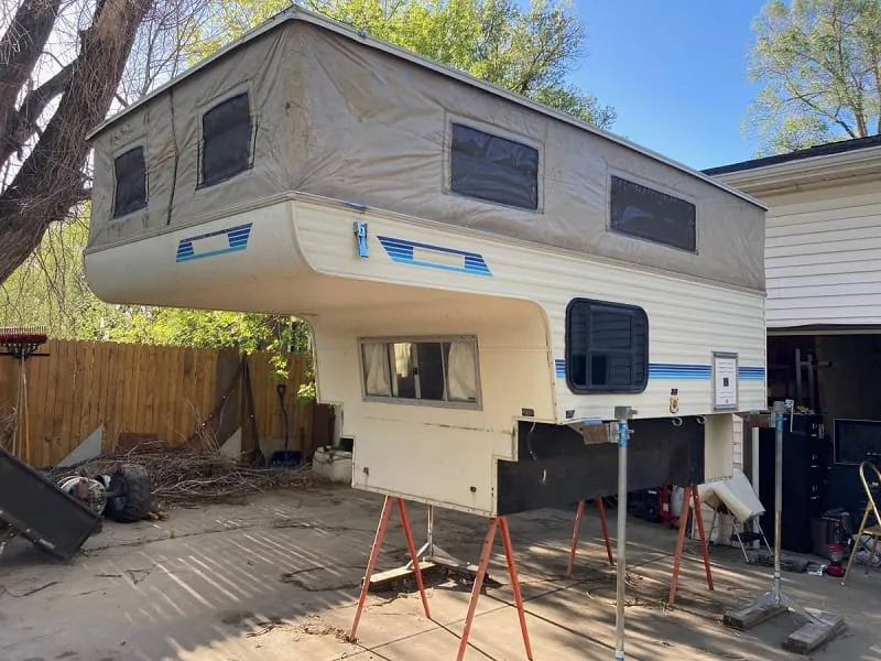 Budget Truck Campers Under $15,000: What I Found in 2026 5 Used pop-up truck camper for sale on jacks in a driveway, typical of Craigslist and marketplace listings