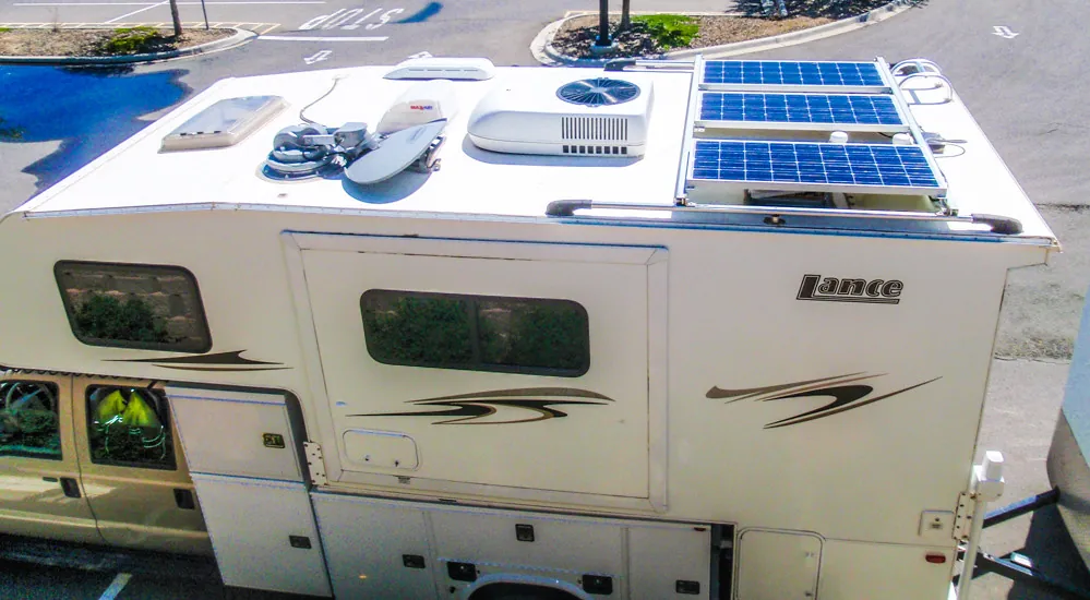 Budget Truck Campers Under $15,000: What I Found in 2026 6 Rooftop solar panels installed on an older Lance hard-side truck camper