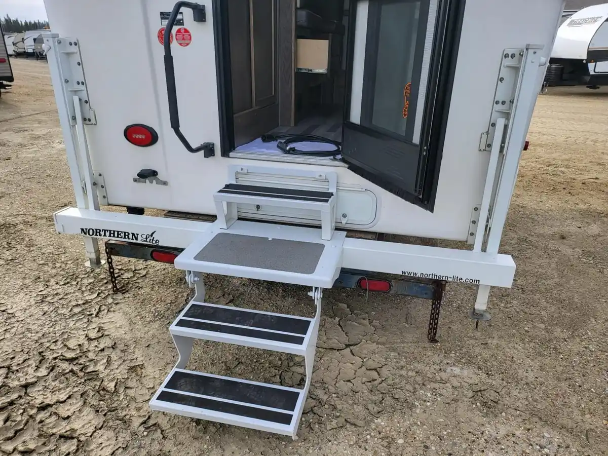 Can You Ride in a Truck Camper? The 2026 State-by-State Guide 2 Rear entry door of a slide-in truck camper with steps