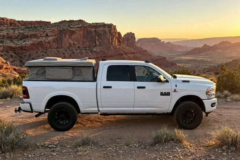 White Ram 2500 truck with a pop-up truck camper parked level at a desert overlook at sunset, a proper Ram 2500 truck camper payload setup