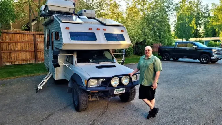 Truck camper loaded on a pickup truck parked in a home driveway at dusk