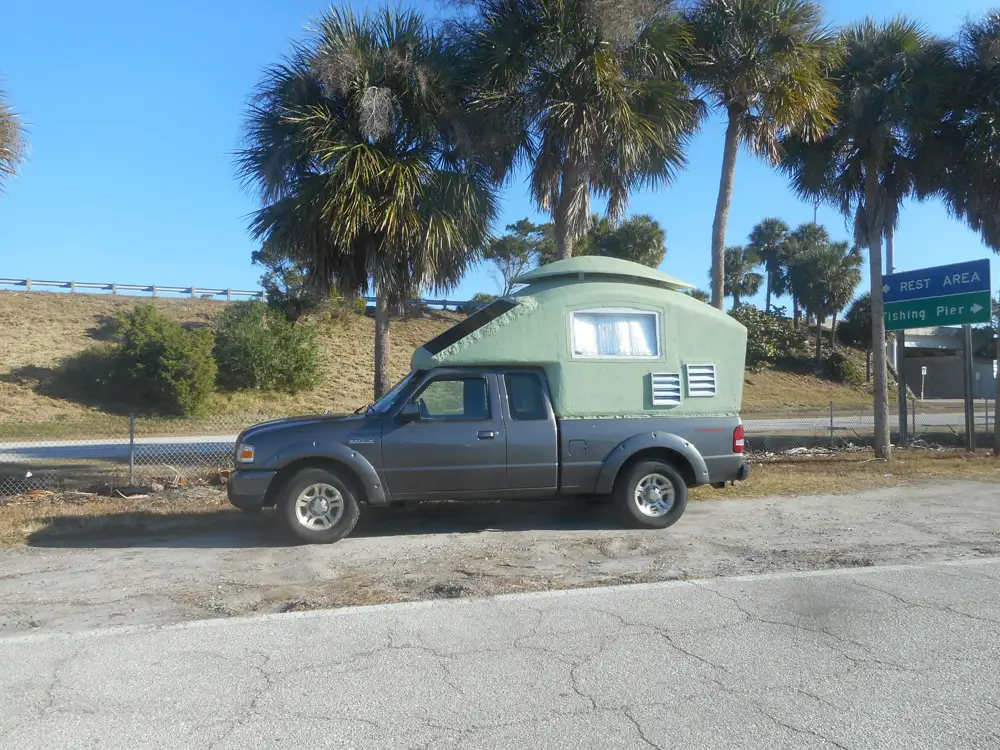 Homemade DIY truck camper mounted on a Ford Ranger pickup, finished exterior in a side profile view.