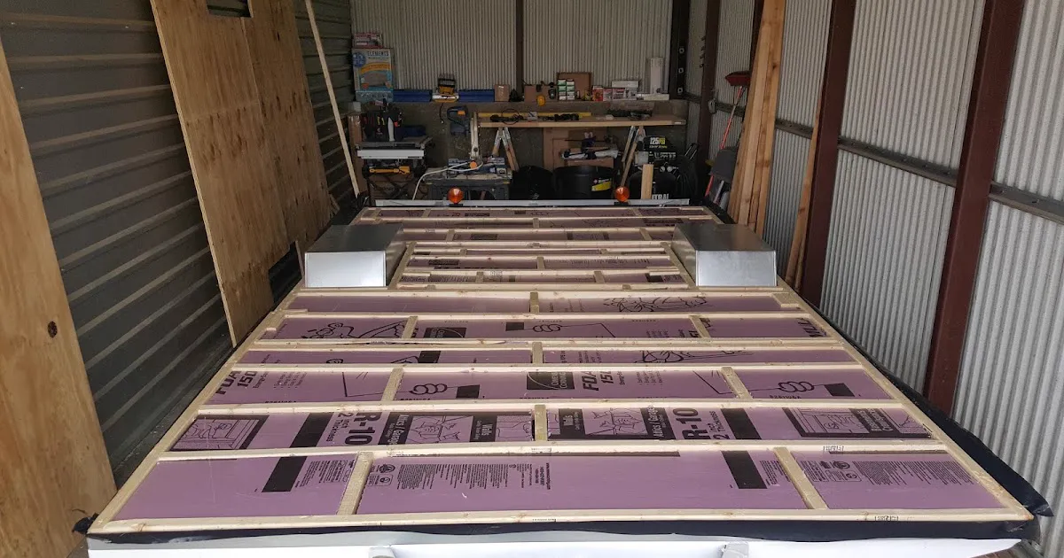 Insulated sandwich floor pack with wooden joists and foam insulation boards being assembled in a workshop.