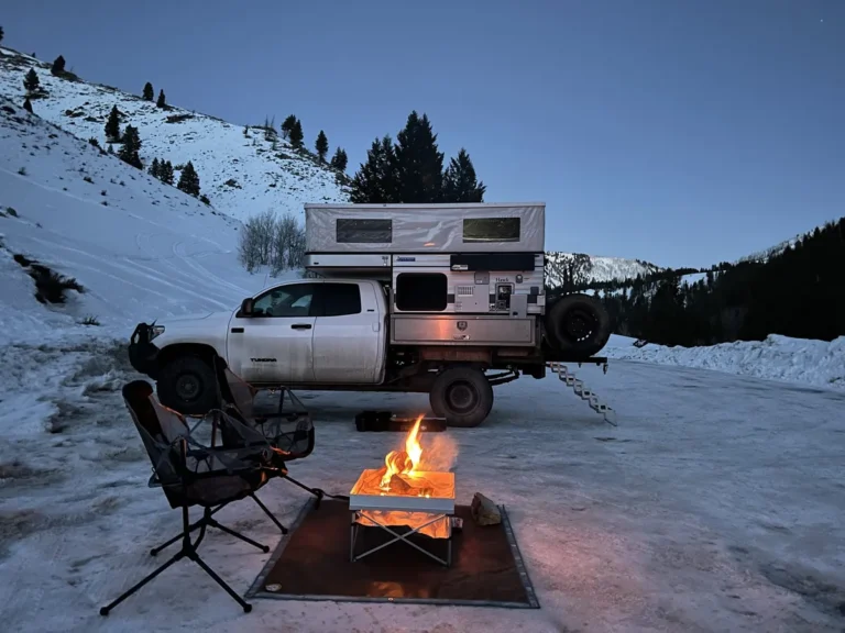 Truck camper winter camping in deep snow at dusk
