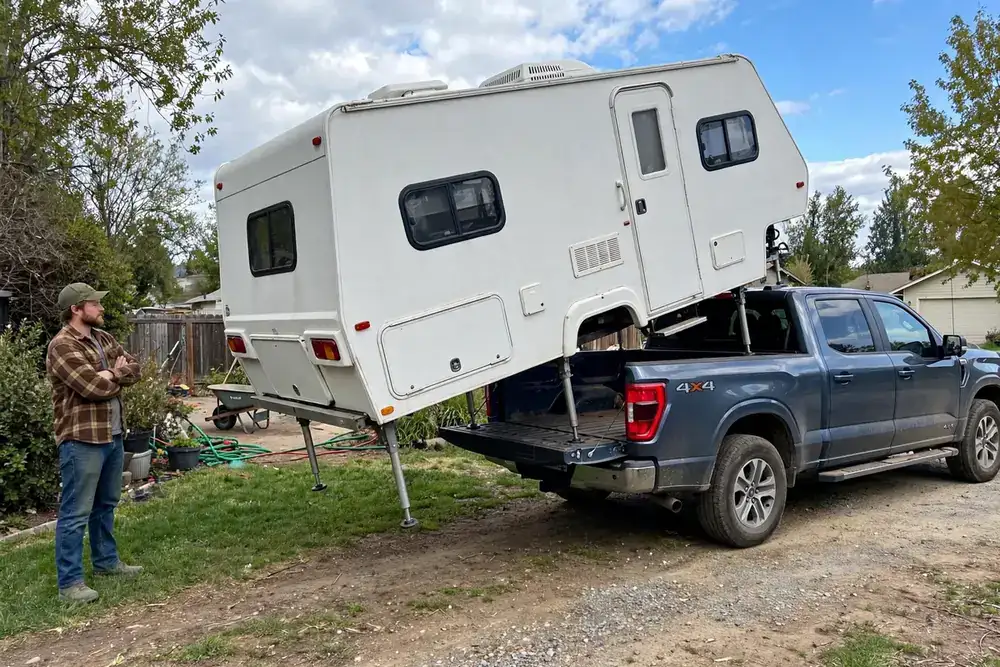 How to Load a Truck Camper by Yourself: The Nose-High Rule, Wind Limits, and When to Abort 5 Owner standing clear watching a truck camper lowered rear-first onto a pickup truck bed