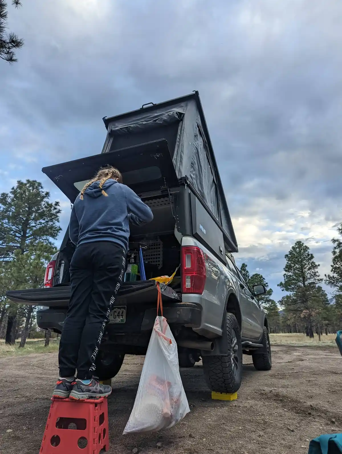 Truck Camper for Tall People: What Actually Works at 6'2" and Up 6 Person climbing into a pop-up truck camper through the short rear door