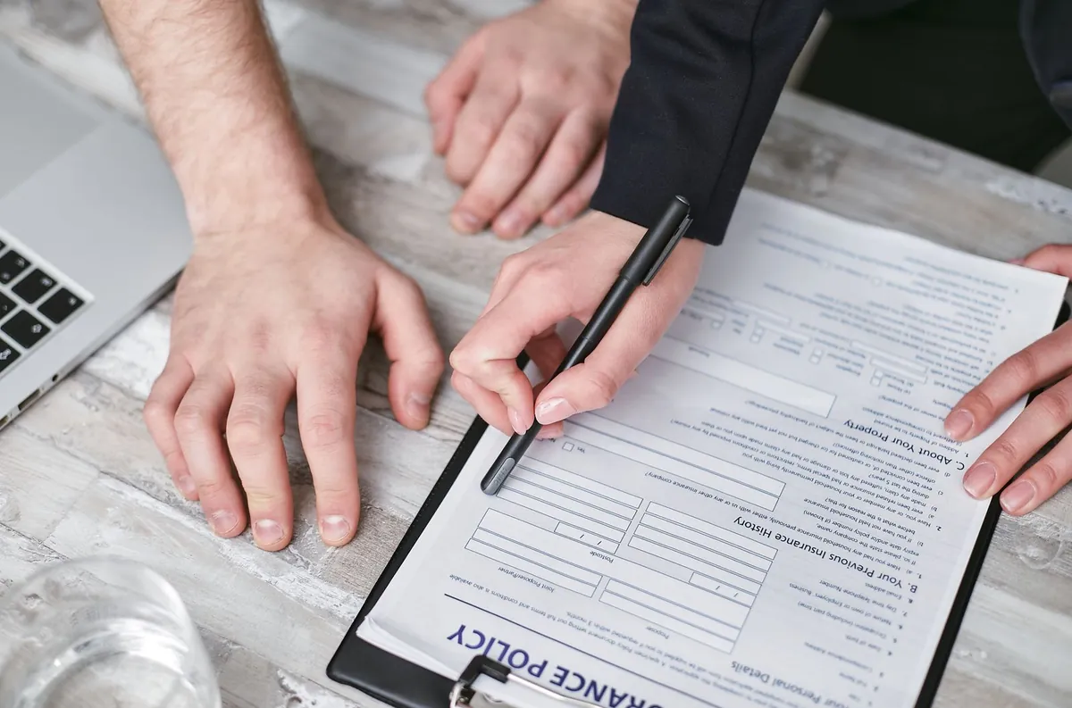 Hand holding a pen over an insurance policy declarations page with shallow depth of field