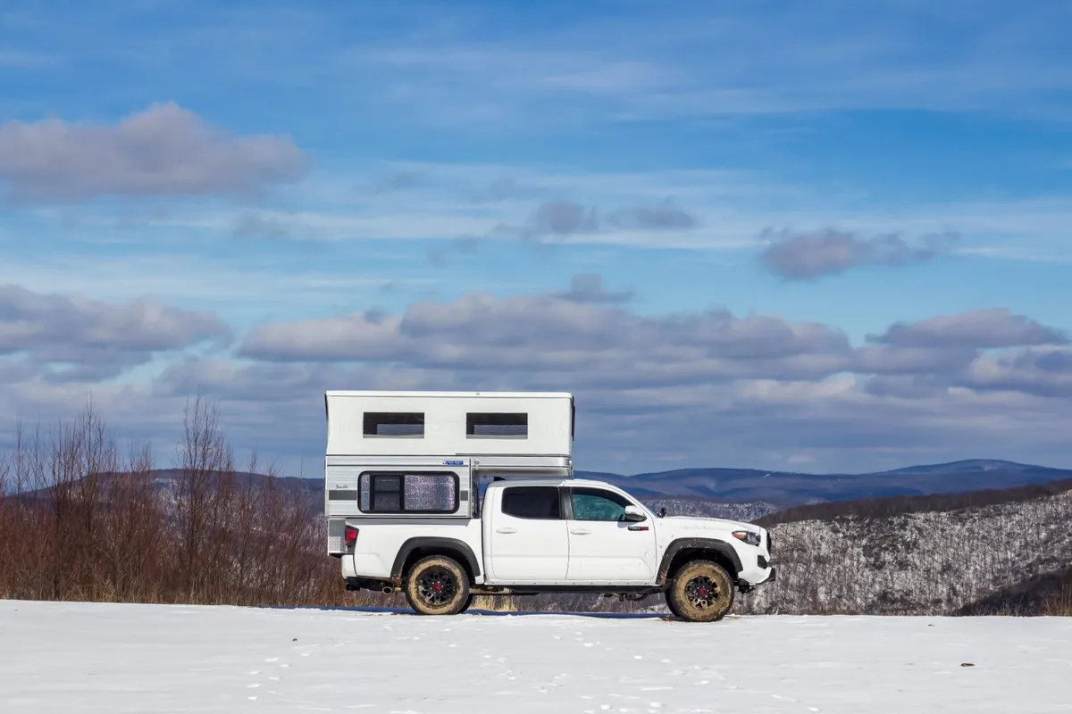Truck Camper Payload Calculator: How to Know If Your Truck Can Carry Your Camper 6 Lightweight Four Wheel Camper Swift pop-up truck camper on a white Toyota Tacoma in a snowy mountain setting