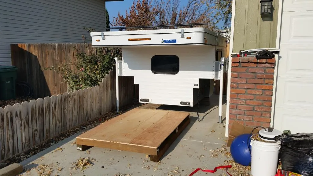 Truck Camper Theft Prevention: A Security Guide That Actually Works 2 A pop-up truck camper raised on its corner jacks in a driveway, showing how quickly a camper can be lifted and loaded