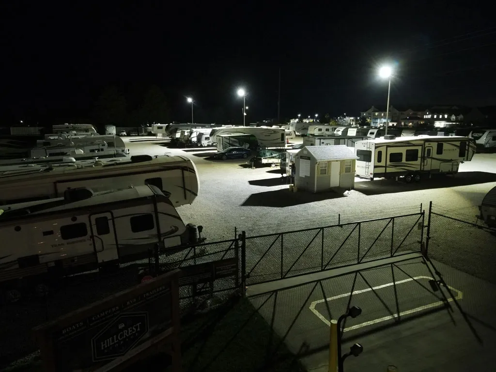 Truck Camper Theft Prevention: A Security Guide That Actually Works 6 A fenced RV storage facility at night with rows of campers under bright lot lighting