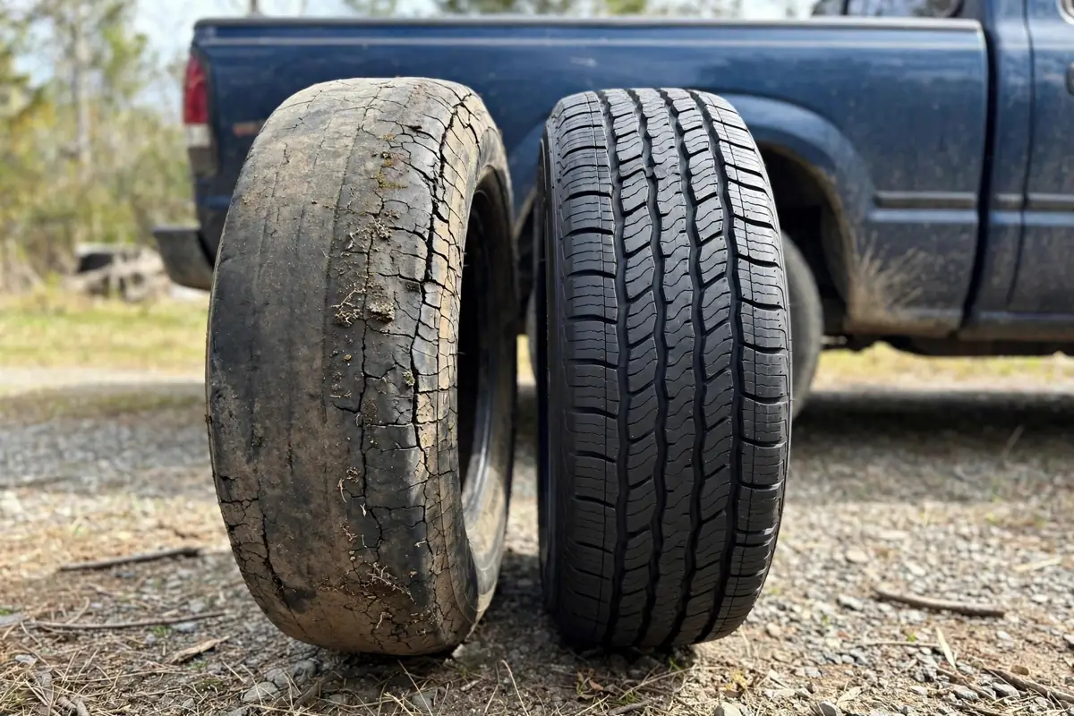 Worn tire with cracked sidewall standing next to a new tire with fresh tread