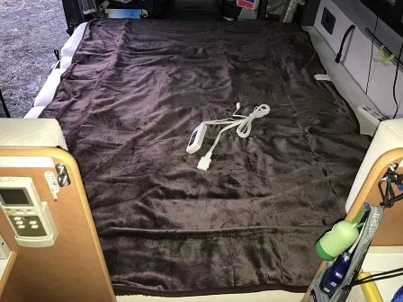 Unbiased Winter Heating Guide: Truck Camper Heater — Diesel vs Propane vs Electric 4 12V electric blanket with wired controller laid out on a camper van bed