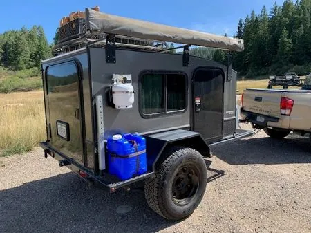 Unbiased Winter Heating Guide: Truck Camper Heater — Diesel vs Propane vs Electric 5 Propane tank and fuel can mounted on the side of a camping trailer at camp