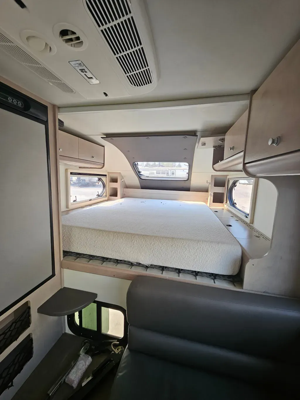 Truck camper cabover bed with the mattress lifted to show airflow matting underneath for ventilation.