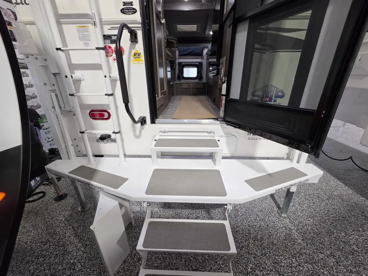 Scissor-style entry steps extended from the rear door of a Northern Lite truck camper.