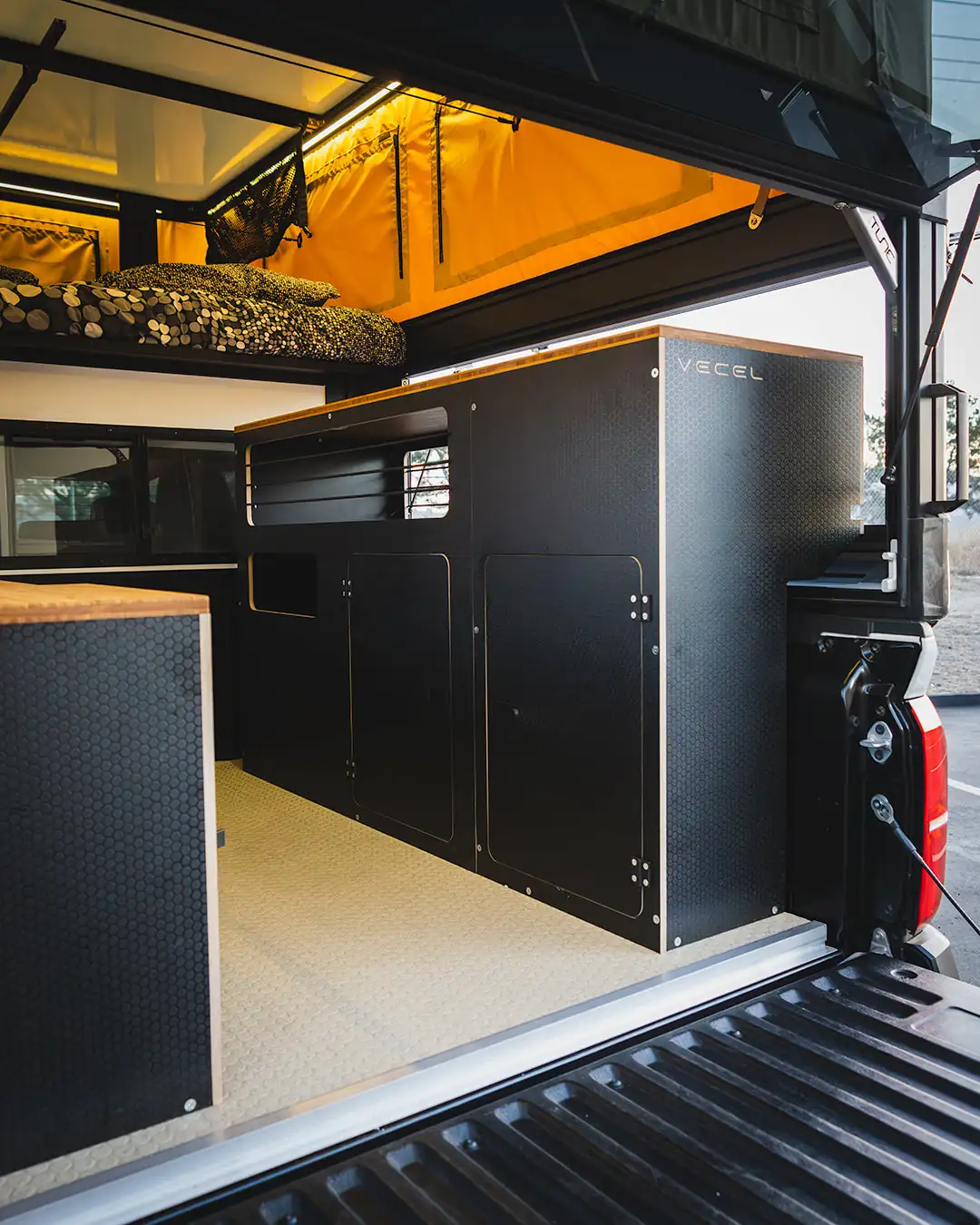 Tune M1 Pop-Up Truck Camper Review: 2026 Hands-On Verdict 3 Tune M1 interior with popped top showing east-west sleeping platform above the living area